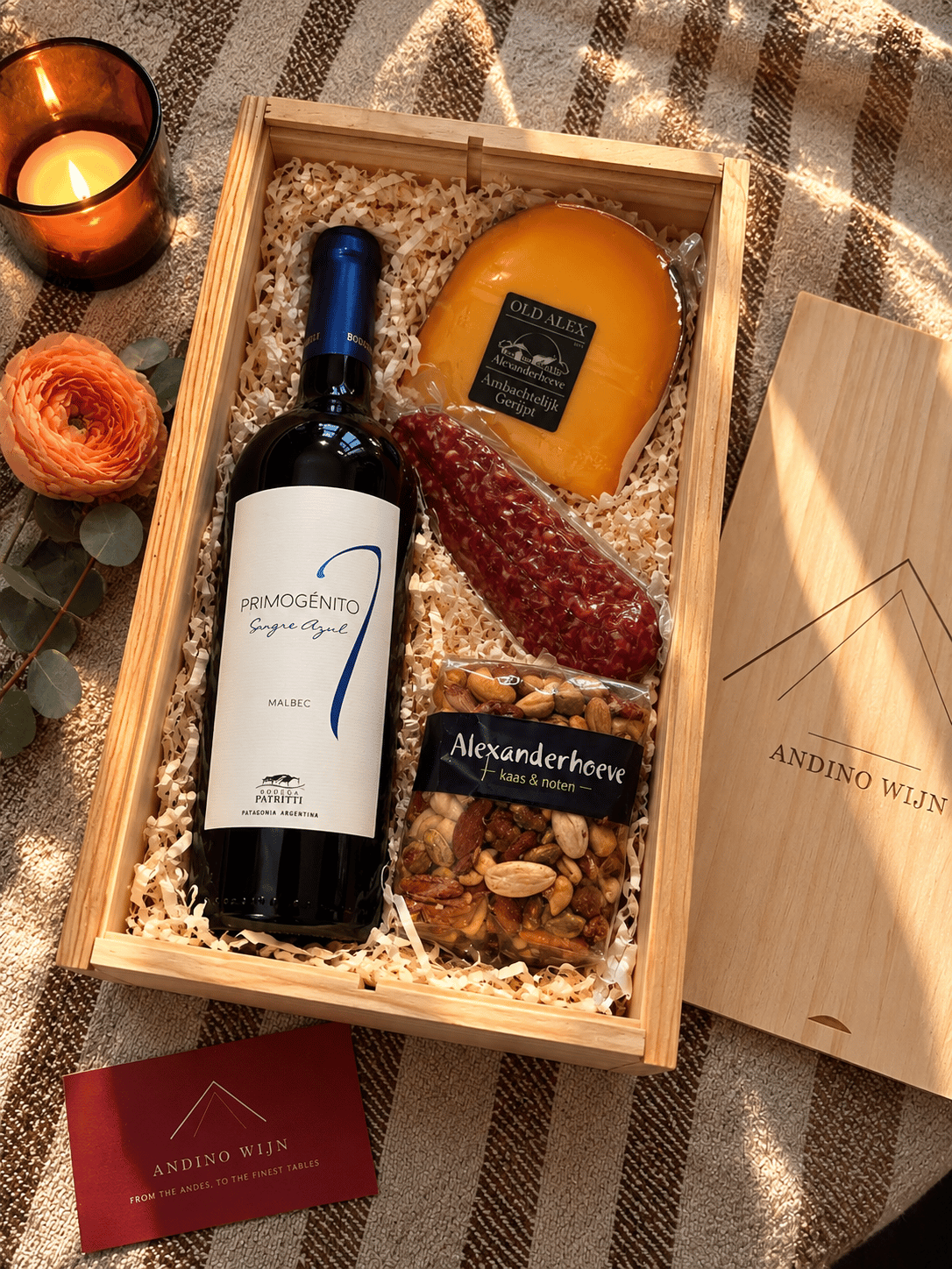 An Andino Wijn corporate gift box holding a bottle of Primogénito Sangre Azul Malbec, a wedge of aged Gouda, sliced Metworst and mixed nuts