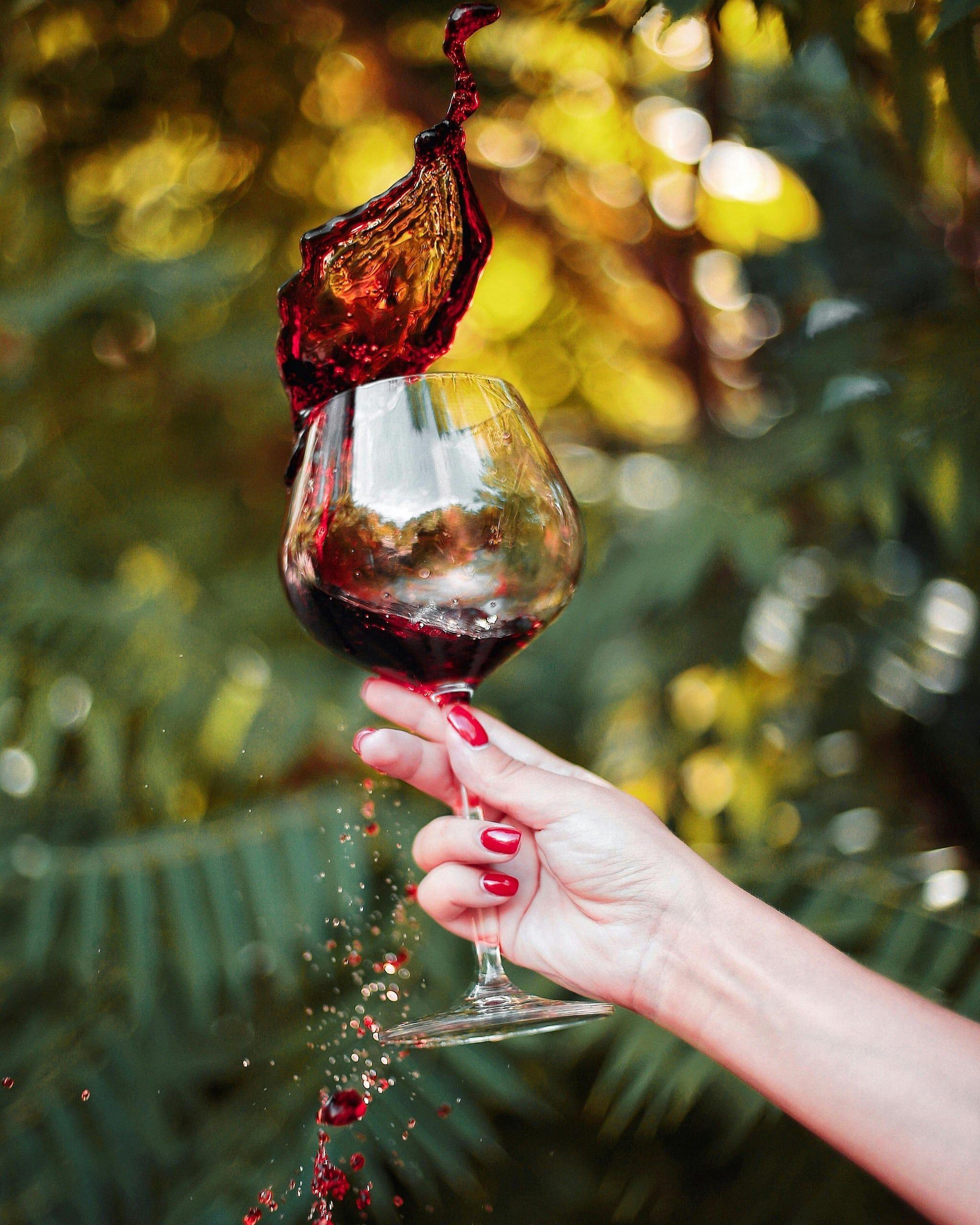 Red wine caught mid-swirl in a glass held against autumn light