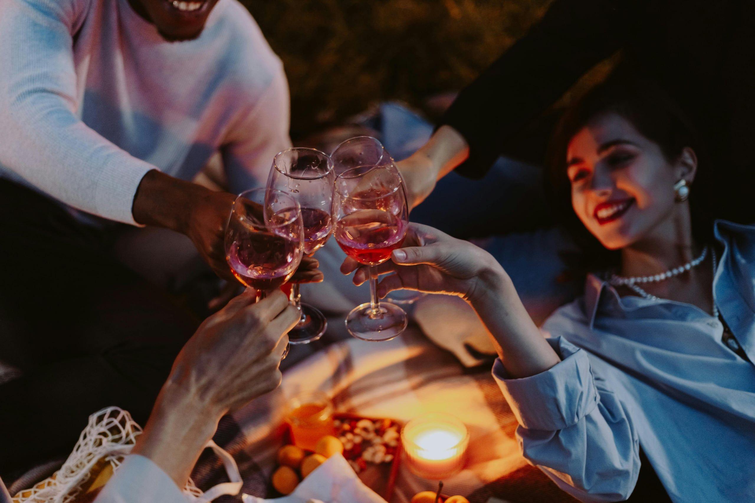 Friends toasting with wine by candlelight on a summer evening