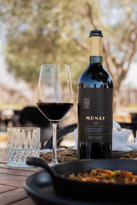 A bottle of Munay wine and a glass of red on an outdoor table in the Cafayate valley